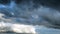 A bird flying against stormy clouds on a summer day. Concept. Bottom view of heavy beautiful clouds flowing in the blue