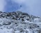 Bird flying over the cliff side of mountain