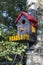 Bird house with red roof, yellow window and fence