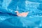 Bird origami of pink paper among a blue plastic bag as if on waves of water or blue sky. Conceptual photo