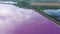 Bird's eye view of pink lake. Clouds and wind turbines are reflected in the lake