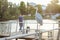 A bird sits on a bridge on a pier by the river in the city near an angler at sunset crane