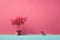 a bird stands next to a potted plant in front of a pink wall