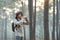 Bird watcher is looking through binoculars while exploring in the pine forest for surveying and discovering the rare biological