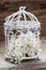 Birdcage with flowers inside on rustic wood