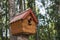 A birdhouse on a tree, a squirrel house, a wooden birdhouse made of small logs. Handmade. Save the animals