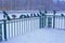 Birds doves in the winter freeze, sit on the metal grille of the fence near the icy lake