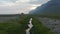 Birds eye drone flying over small river in green highlands in Iceland. Aerial view of stunning grassy countryside in