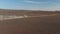 Birds eye drone following car speeding along dirt road in Iceland rocky desert stirring up dust cloud. Aerial view 4x4