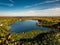 Birds eye view of autumn forest and a small lake. Aerial colorful forest scene in autumn with orange and yellow foliage.