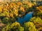 Birds eye view of autumn forest and a small lake. Aerial colorful forest scene in autumn with orange and yellow foliage.