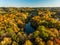 Birds eye view of autumn forest and a small lake. Aerial colorful forest scene in autumn with orange and yellow foliage.