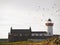 Birds flying over old white lighthouse, Mutton Island, Galway city Ireland. Cloudy sky