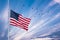 Birds flying in the shape of v on the cloudy sunset sky. American flag against a blue cloudy sky.