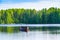 Birds perched on a fishing boat on a lake by a pine forest