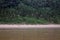 Birds on the sandy shoreline of the Tambopata River lined by trees and grasses of the Amazon rainforest in Peru, South America