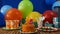 Birthday 25 cake on rustic wooden table with background of colorful balloons, gifts, plastic cups, plastic plate