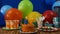 Birthday 87 cake on rustic wooden table with background of colorful balloons, gifts, plastic cups, plastic plate