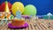 Birthday 9 cake with candles on rustic wooden table with background of colorful balloons, gifts, plastic cups and candies