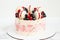 Birthday or anniversary cake with cream cheese frosting decorated with macaroons, blueberries and raspberries. Gold splash on the
