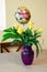 Birthday bunch of yellow roses in a purple vase in front of window