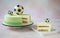 Birthday cake with chocolate football balls on top and a piece of cake with a beautiful cut lies on a square plate - close-up and