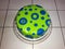 Birthday cake circular glazed, green and blue decoration, placed on a glass tray