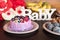 Birthday cake and muffins with wooden greeting sign on dark background. Wooden sing with letters Baby and holiday sweets