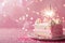 Birthday cake with pink frosting and a sparkling candle, set against a glittery pink backdrop, perfect for girl's