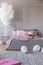 Birthday cake on wooden grey on king size bed with grey bedding and pink pillows and blanket in trendy interior with bunch of