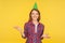 Birthday celebration. Portrait of happy beautiful ginger girl with funny party cone on head showing questioning gesture with