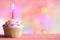 Birthday cupcake and candle on colorful defocused background party concept