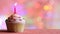 Birthday cupcake and candle on colorful defocused background party concept