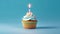 Birthday cupcake with a candle  on light blue background with balloons. Generative Ai