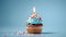 Birthday cupcake with a candle  on light blue background with balloons. Generative Ai
