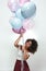 Birthday girl. Vertical portrait of young happy afro american woman holding a bunch of colourful balloons and looking up