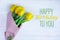 Birthday greeting card with yellow tulips and the inscription on a light wooden background. Greeting card for posting