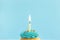 Birthday greeting concept. Burning candle on muffin, cupcake. Blue background