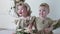 Birthday sisters in dresses sitting on photoshoot in studio on background of wall with decor