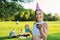 Birthday, teenage girl in festiv hat with cake and candle at outdoor party