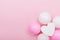 Birthday or wedding mockup with white heart shape, confetti and pastel balloons on pink table from above. Flat lay composition.