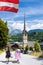 Bischofshofen with couple of women in traditional costumes against main church in Tyrolian Alps, Austria