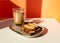 Biscotti almond cookies and a cup of coffee on the table on orange background. Geometric minimalist composition with shadow