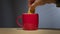 Biscuit dunked into hot drink in a bright red coffee mug