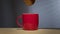 Biscuit dunked into hot drink in a bright red coffee mug