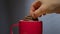 Biscuit dunked into hot drink in a bright red coffee mug