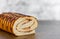 Biscuit roll covered with chocolate closeup on wooden table on gray wall background