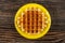 Biscuit waffle in yellow saucer on wooden table. Top view