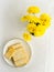 Biscuits and small bouquet of yellow spring flowers on white tablecloth