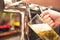 Bistro waiter serving a cold beer. Hand of barman pouring a lager beer from tap